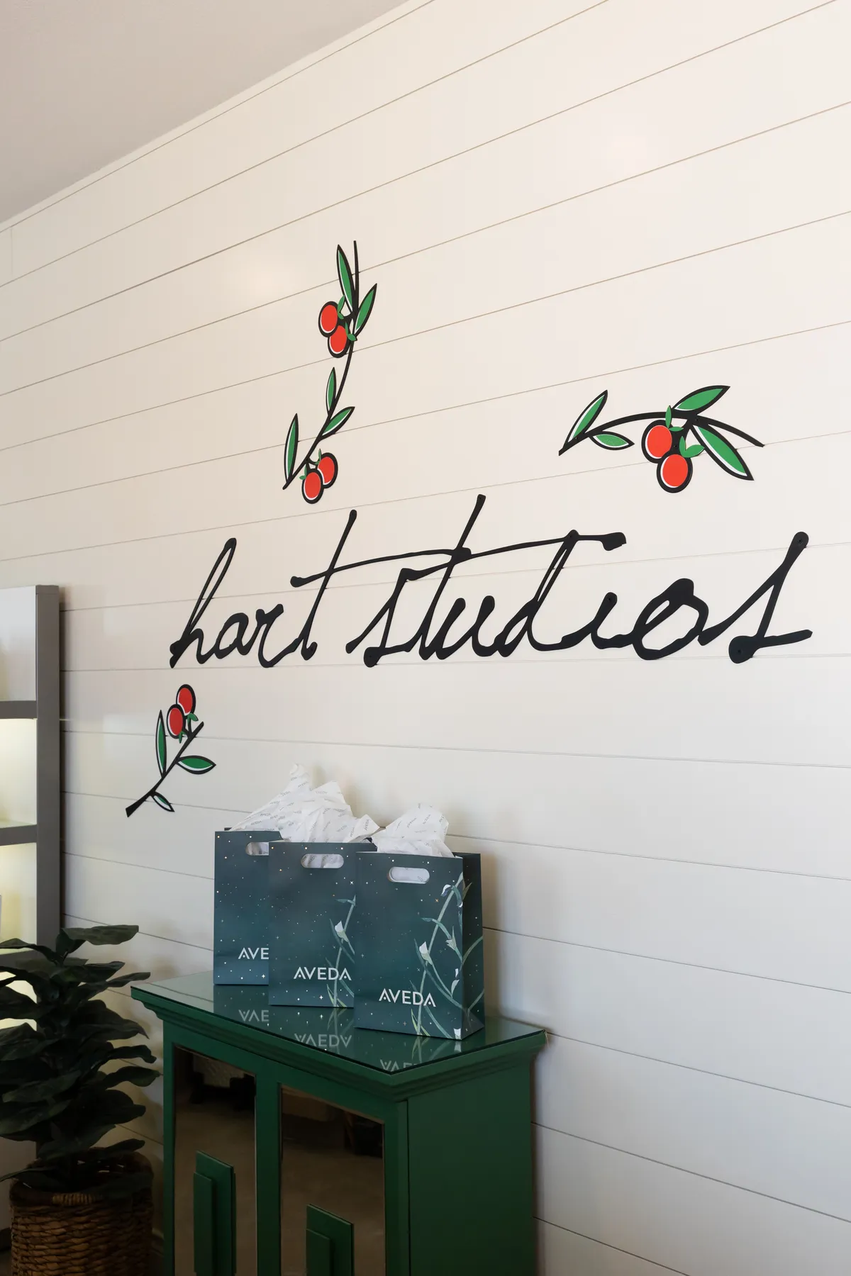 Hart Studios script and citrus artwork above Aveda bags at the front desk