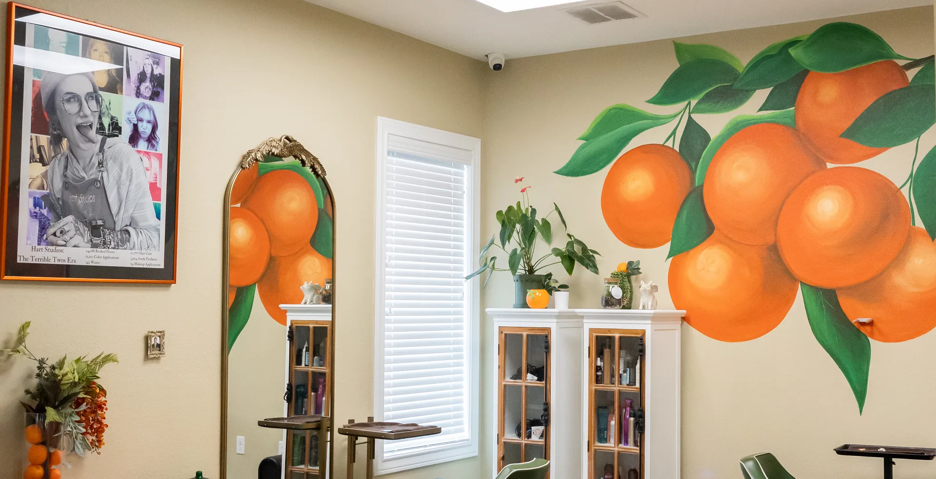 Orange citrus mural, gold-framed mirror, and styling stations inside Hart Studios